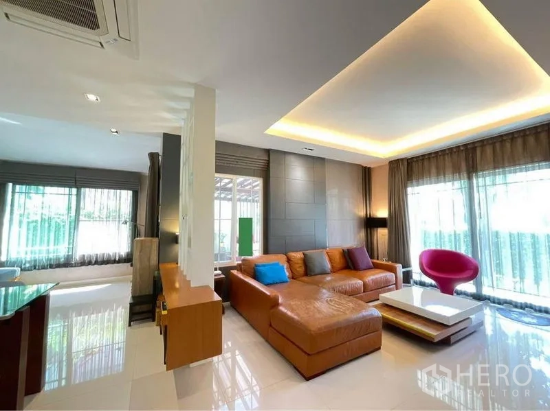 独立式住宅 出售在Prawet, Bangkok - 宽敞客厅，L型真皮沙发、落地窗与嵌入式天花灯。