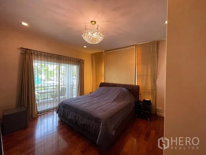 Detached House for sale in Lat Krabang, Bangkok - Master bedroom with chandelier, wood floors and access to a private balcony.