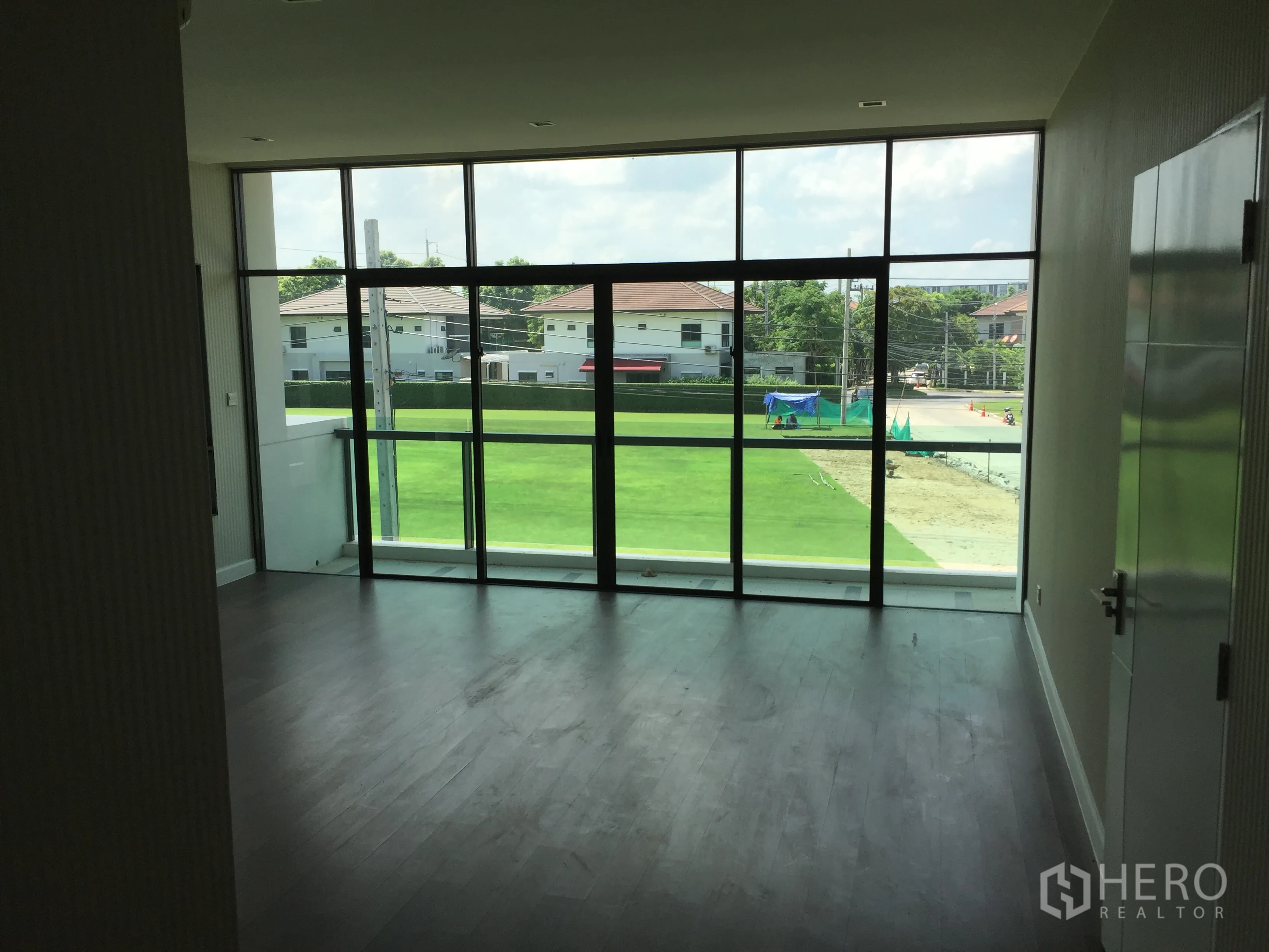 独立式住宅 出租或出售在Prawet, Bangkok - 宽敞主卧，全景落地玻璃俯瞰修剪整齐的草坪。