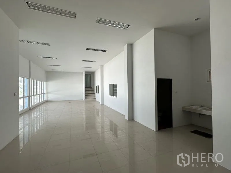 Factory for rent in Bang Bo, Samut Prakan - Office hall with built-in sink, staircase to the upper level and multiple windows.