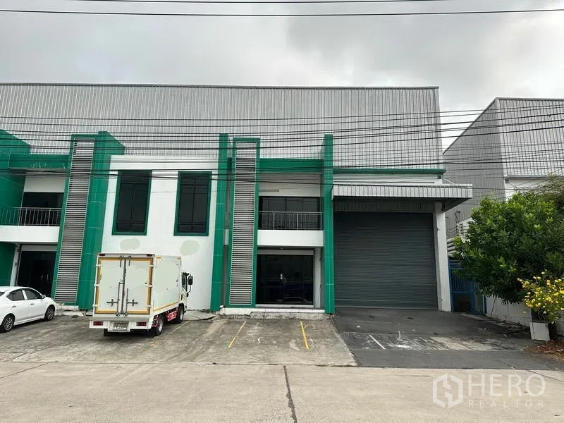 工厂 出租或出售在Bang Phli, Samut Prakan - 邦普里绿白配色工厂外立面，带卷帘门、装卸区与停车位