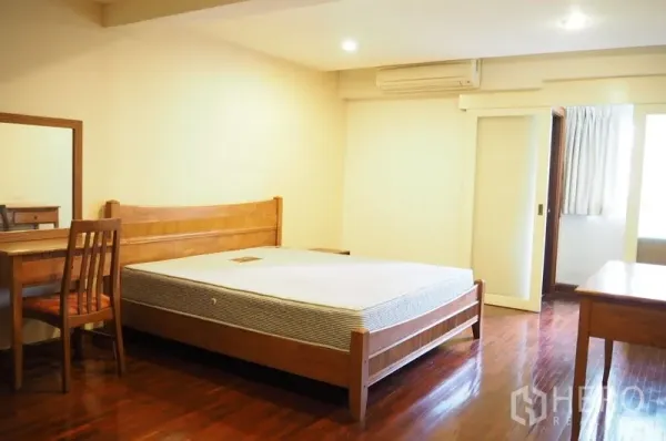 คอนโด ให้เช่าในPathum Wan, Bangkok - ห้องนอนกว้างเตียงไม้ โต๊ะทำงาน และประตูสู่ห้องน้ำในตัว