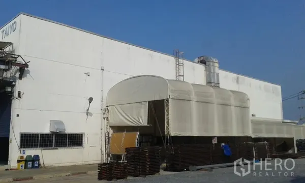 Factory for rent in Uthai, Phra Nakhon Si Ayutthaya - Large white factory exterior in Uthai, Ayutthaya with covered loading bay, vent stack and paved yard.