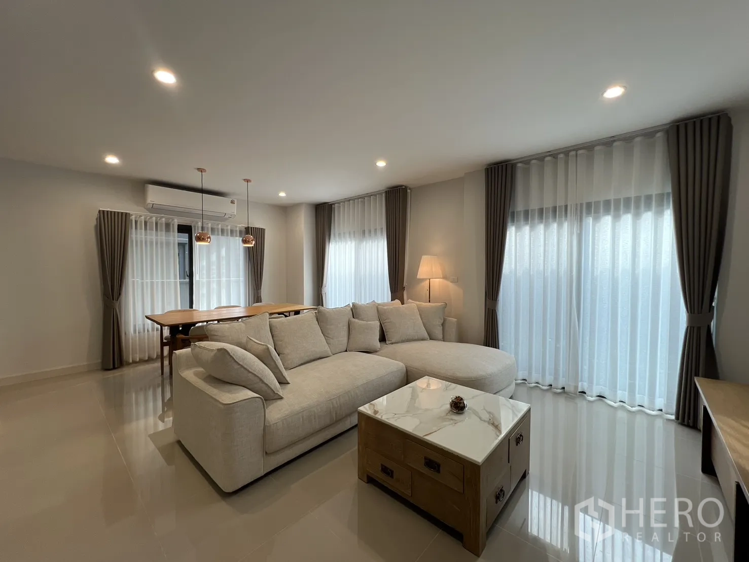 独立式住宅 出租在Prawet, Bangkok - 采光充足的开放式客厅，米色沙发与餐桌。