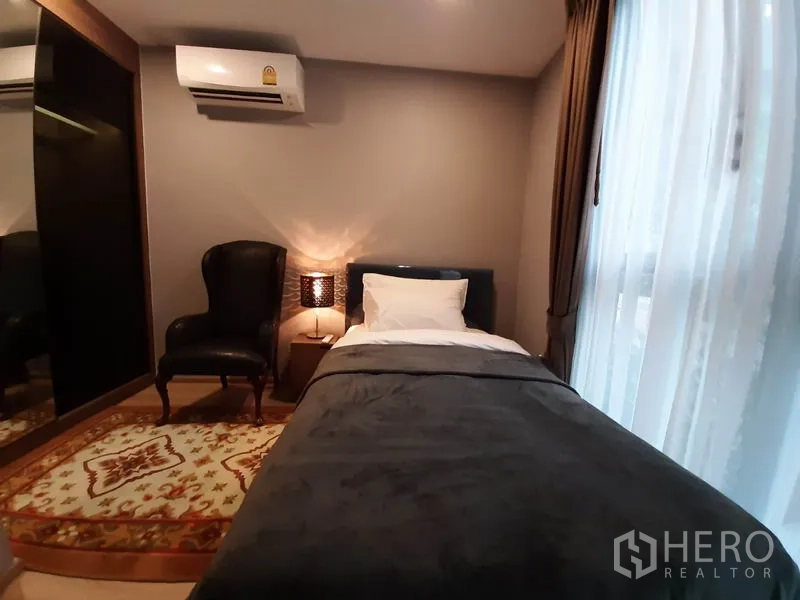 公寓 出租或出售在Watthana, Bangkok - 次卧配单人床、扶手椅、衣柜与落地窗。
