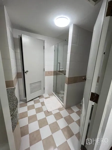 Condominium for rent or sale in Watthana, Bangkok - Bathroom with glass-enclosed shower, tiled walls and checked floor pattern.