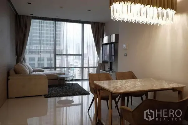 公寓 出租在Sathon, Bangkok - 客厅连餐区，L 形沙发、电视柜与城市景观落地窗。