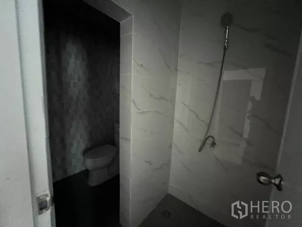 Shophouse for rent in Khlong Toei, Bangkok - Shower area with handheld shower next to a separate toilet alcove with tiled walls.