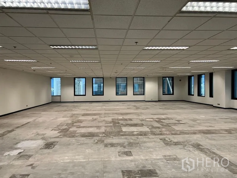 办公空间 出租在Khlong Toei, Bangkok - 开放式办公区，拼接地面，众多窗户俯瞰曼谷高楼，格栅吊顶之下。