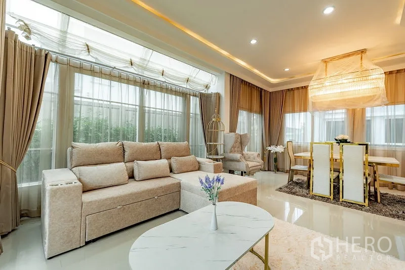 บ้าน ให้เช่าหรือขายในBang Khen, Bangkok - โซนรับแขกและทานอาหาร กระจกเต็มบานรอบด้าน โซฟาเบจ และโคมไฟดีไซน์เด่น