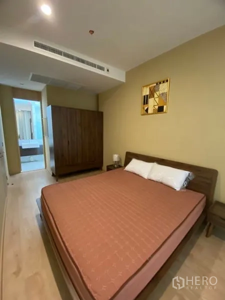 Condominium for rent in Watthana, Bangkok - Bedroom with queen bed, wardrobe and view toward the bathroom entrance.