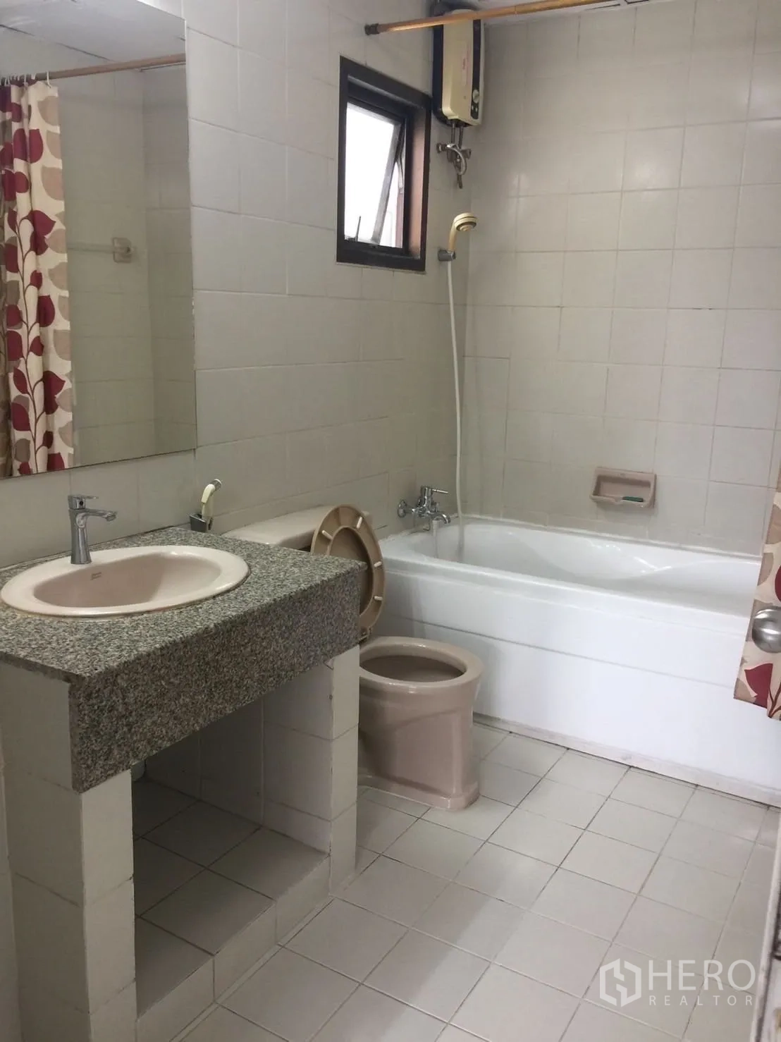 Condominium for rent or sale in Watthana, Bangkok - Tiled bathroom with bathtub-shower combo, stone-top sink and a window.