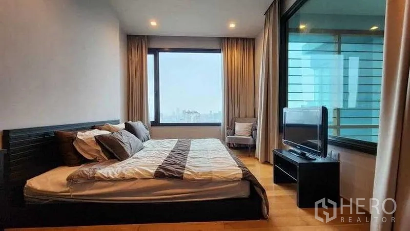Condominium for rent in Khlong Toei, Bangkok - Master bedroom with large window, TV console and city outlook.