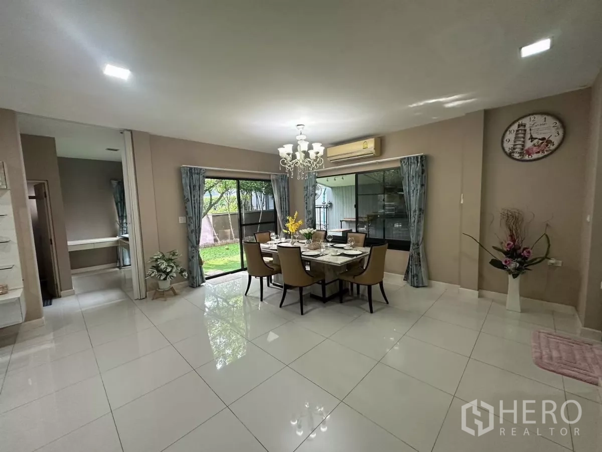 Detached House for rent or sale in Bang Kapi, Bangkok - Dining area with chandelier lighting and wide glass doors opening to the lawn.