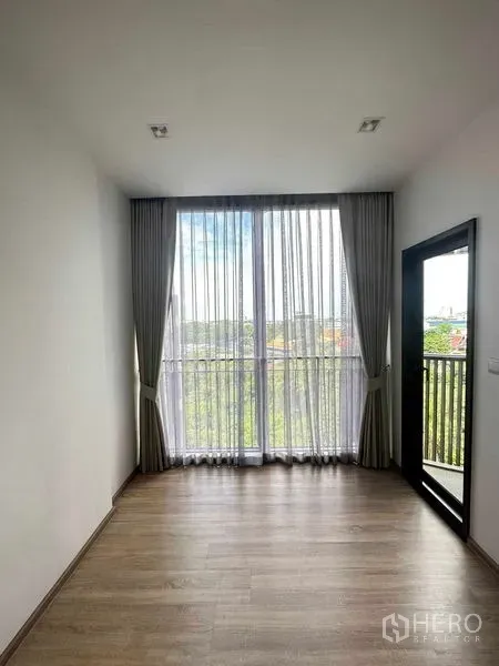 公寓 出售在Watthana, Bangkok - 带阳台门的房间，通高窗与纱帘，远眺树梢景观。