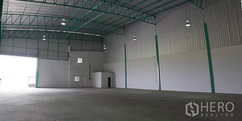 货栈 出租在Khlong Luang, Pathum Thani - 仓库内部挑高空间，钢结构屋架、平整混凝土地面与大型卷闸门。