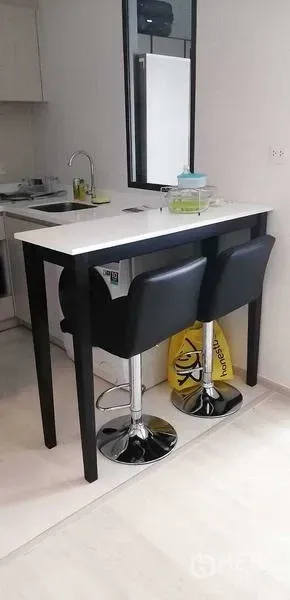 公寓 出租或出售在Pathum Wan, Bangkok - 纤细吧台配两把黑色吧椅，临近紧凑小厨房。