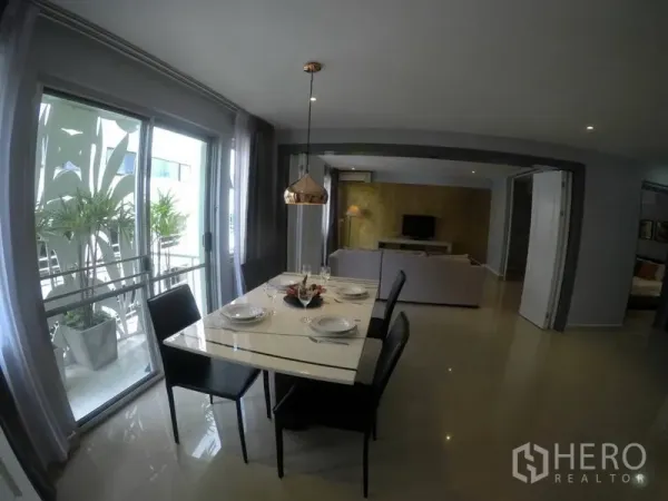 Condominium for rent in Watthana, Bangkok - Dining area set for four beside a balcony with greenery, opening to the living room.
