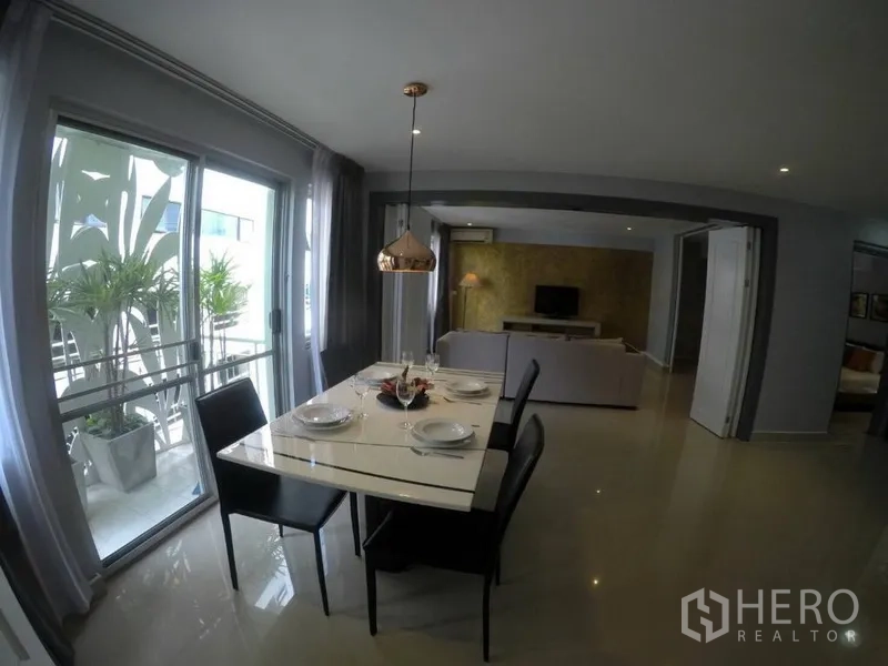 Condominium for rent in Watthana, Bangkok - Dining area set for four beside a balcony with greenery, opening to the living room.