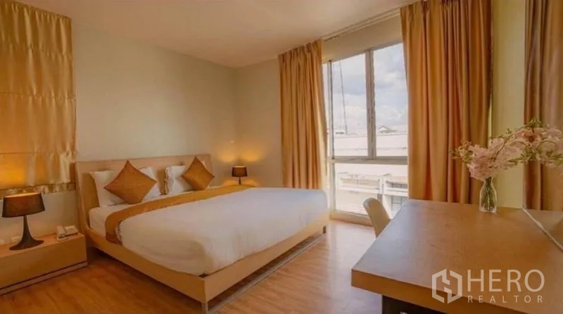 Retail Space for sale in Phra Nakhon, Bangkok - Bright guest room with king bed, work desk, golden curtains and a large window.