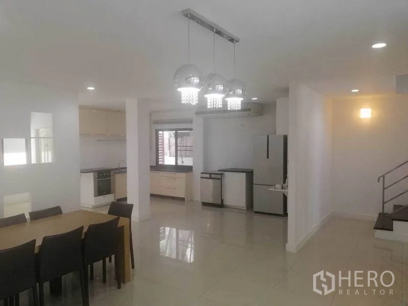 联排别墅 出租在Wang Thonglang, Bangkok - 明亮的厨房与餐区，吊灯与家电齐备。