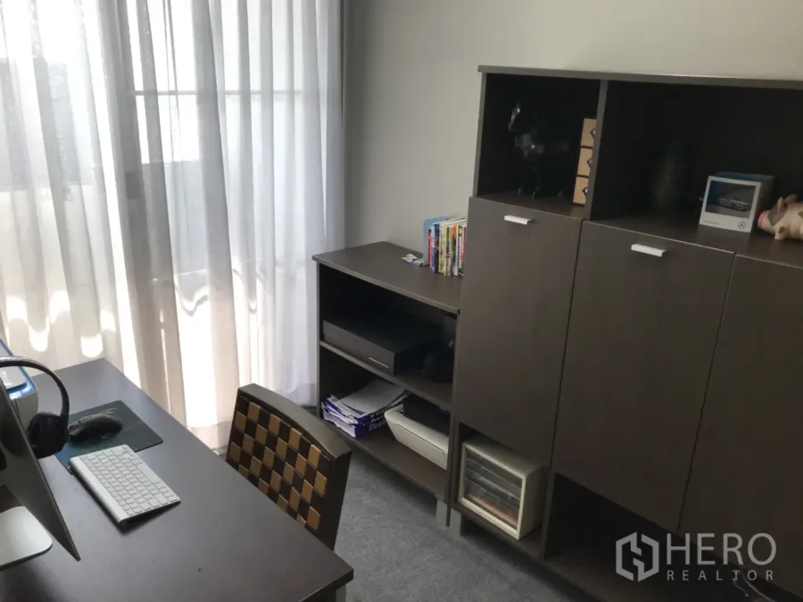 公寓 出租在Watthana, Bangkok - 采光良好的书房，配有书桌、电脑与深色木质收纳柜，临纱帘阳台。