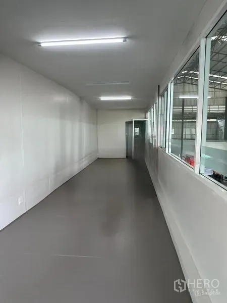 Warehouse for rent in Lat Krabang, Bangkok - Mezzanine office corridor with windows overlooking the warehouse floor and bright LED lighting.