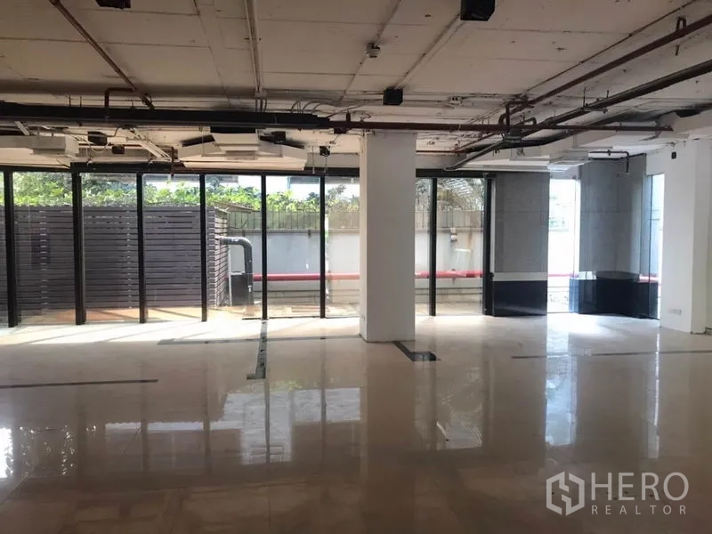 办公空间 出租在Watthana, Bangkok - 明亮工作区，落地窗与中央立柱，自然光洒在光滑地面上