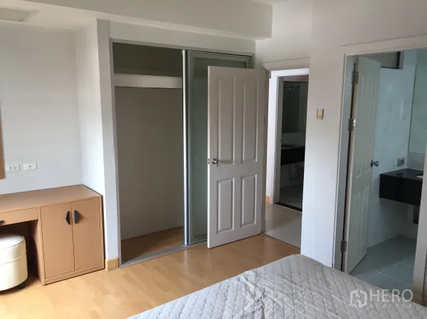 公寓 出租在Watthana, Bangkok - 卧室配木地板、内置衣柜与梳妆台，可直接进入浴室。