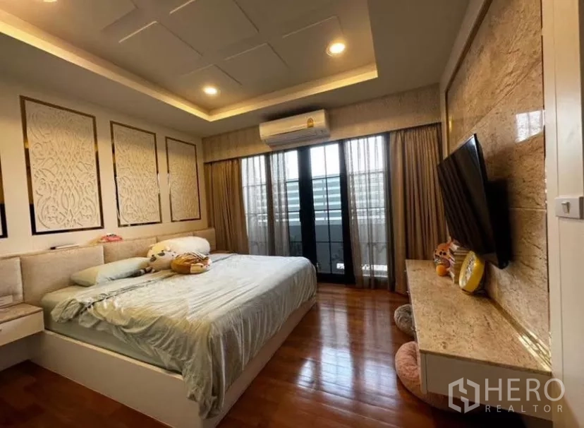 Townhouse for rent in Yan Nawa, Bangkok - Master bedroom with king bed, balcony doors, and a feature TV wall.