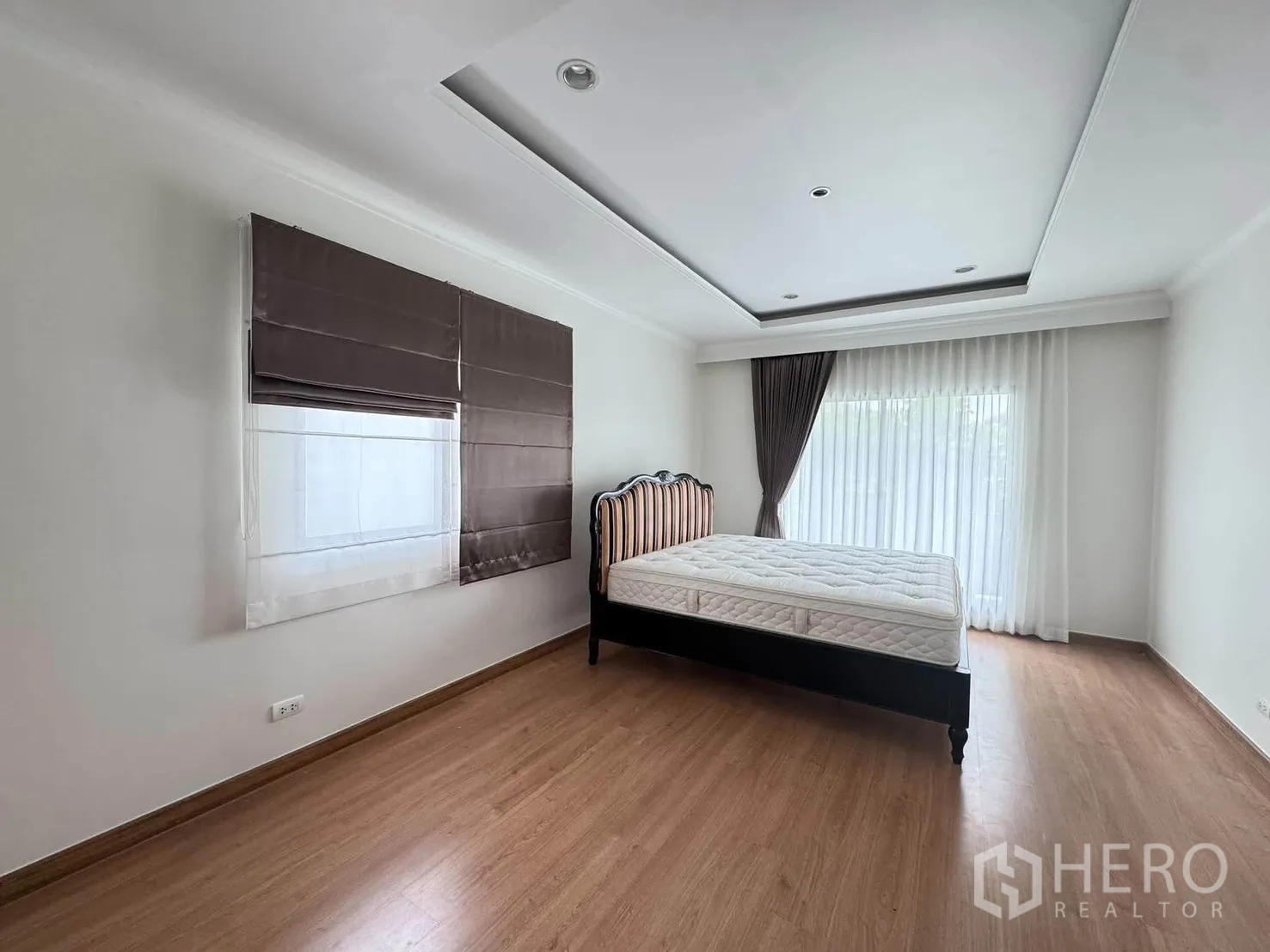 半独立式住宅 for rent or sale in Suan Luang, Bangkok - 宽敞卧室带床架与木地板，纱帘遮挡的推拉门采光好。