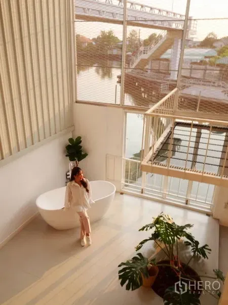 联排别墅 出租在Khlong Toei, Bangkok - 阁楼式中庭，浴缸与绿植点缀，俯瞰水景的帕卡农联排别墅内部。