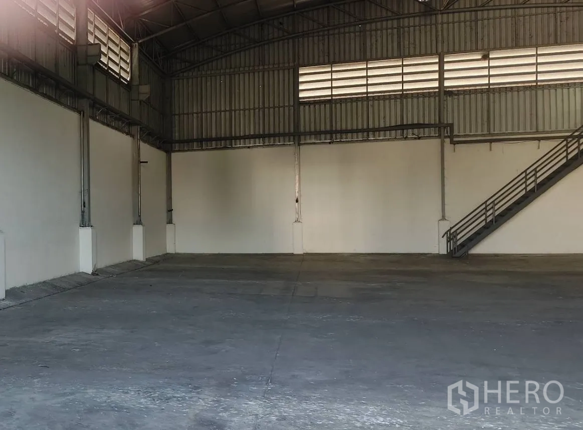Factory for rent in Lat Lum Kaeo, Pathum Thani - Open warehouse floor with high steel roof, white walls and side staircase for office access.