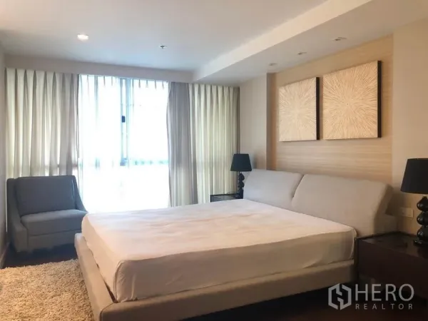 公寓 出租在Pathum Wan, Bangkok - 宽敞卧室，配特大床、装饰画与落地窗帘。