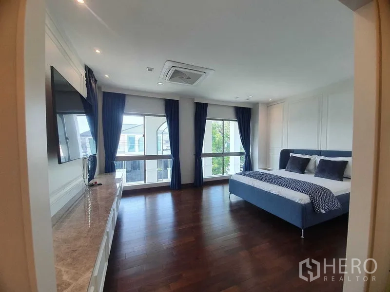 独立式住宅 出租或出售在Lat Krabang, Bangkok - 主卧宽敞，深色木地板，大窗配藏蓝窗帘，蓝色大床。
