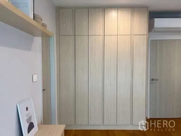 Townhouse for rent or sale in Saphan Sung, Bangkok - Closed floor-to-ceiling wardrobe panels next to an air conditioner and light-colored door.