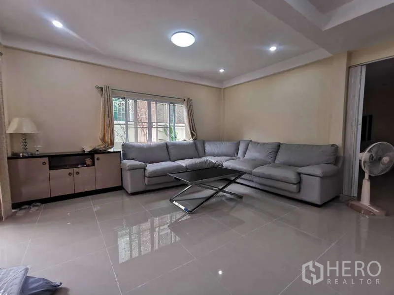 Townhouse for rent in Chatuchak, Bangkok - Second lounge with gray sectional sofa and glossy tile floor.
