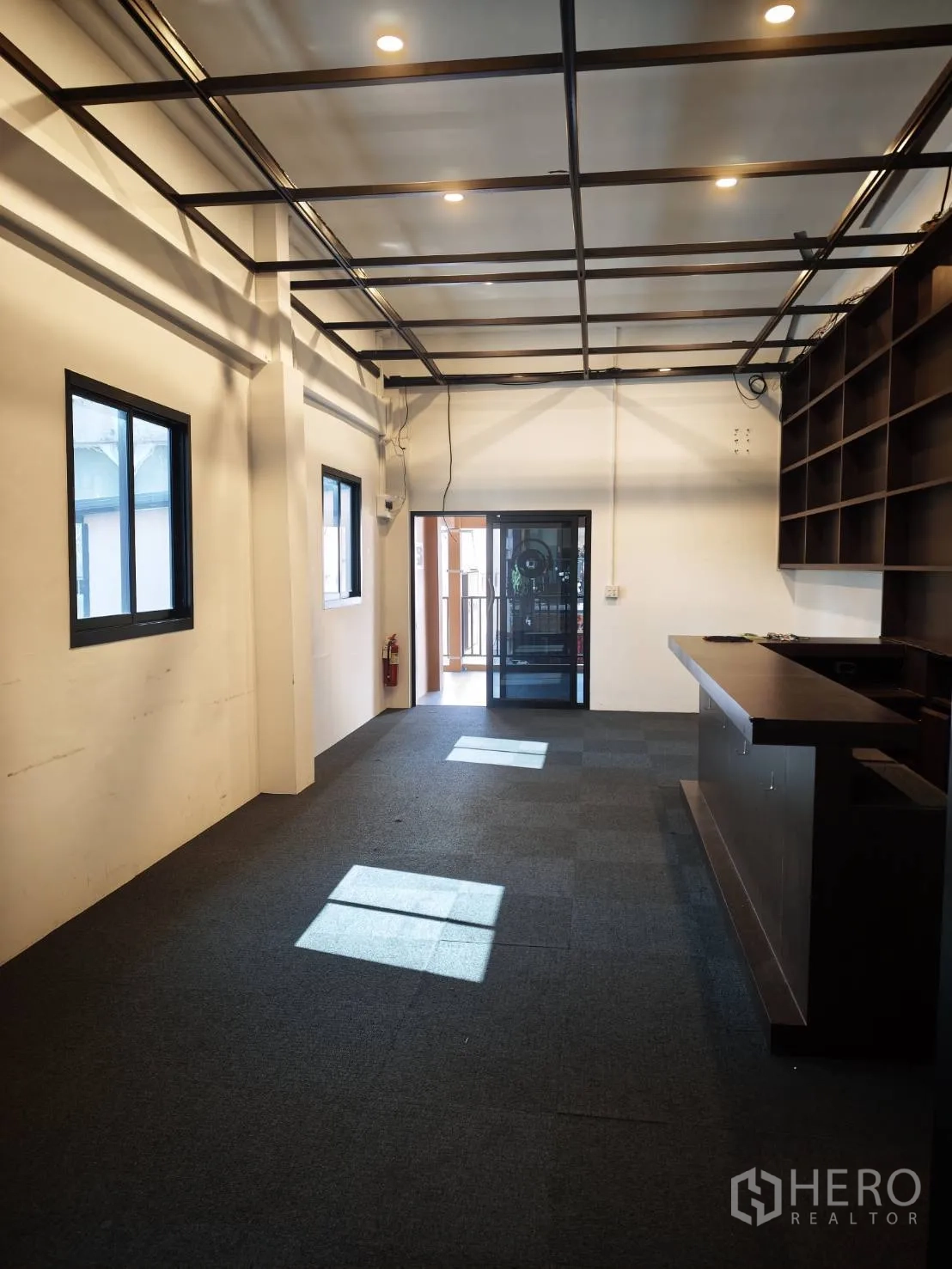 零售空间 for rent in Watthana, Bangkok - 室内朝入口视角，可见窗户、吧台与筒灯。