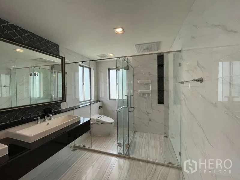 Detached House for rent or sale in Lat Krabang, Bangkok - Bathroom with glass-enclosed rain shower, double vanity and marble-pattern walls.