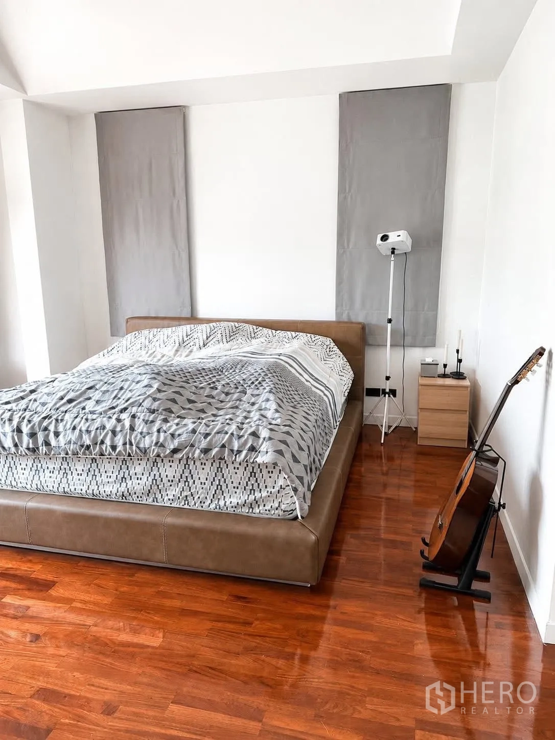 独栋房屋 for rent in Prawet, Bangkok - 极简卧室，低矮床架、吉他架与抛光木地板。