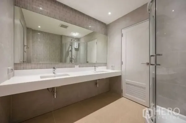 Townhouse for sale in Khlong Toei, Bangkok - Contemporary bathroom with double vanity, large mirror, glass shower and neutral tiles.