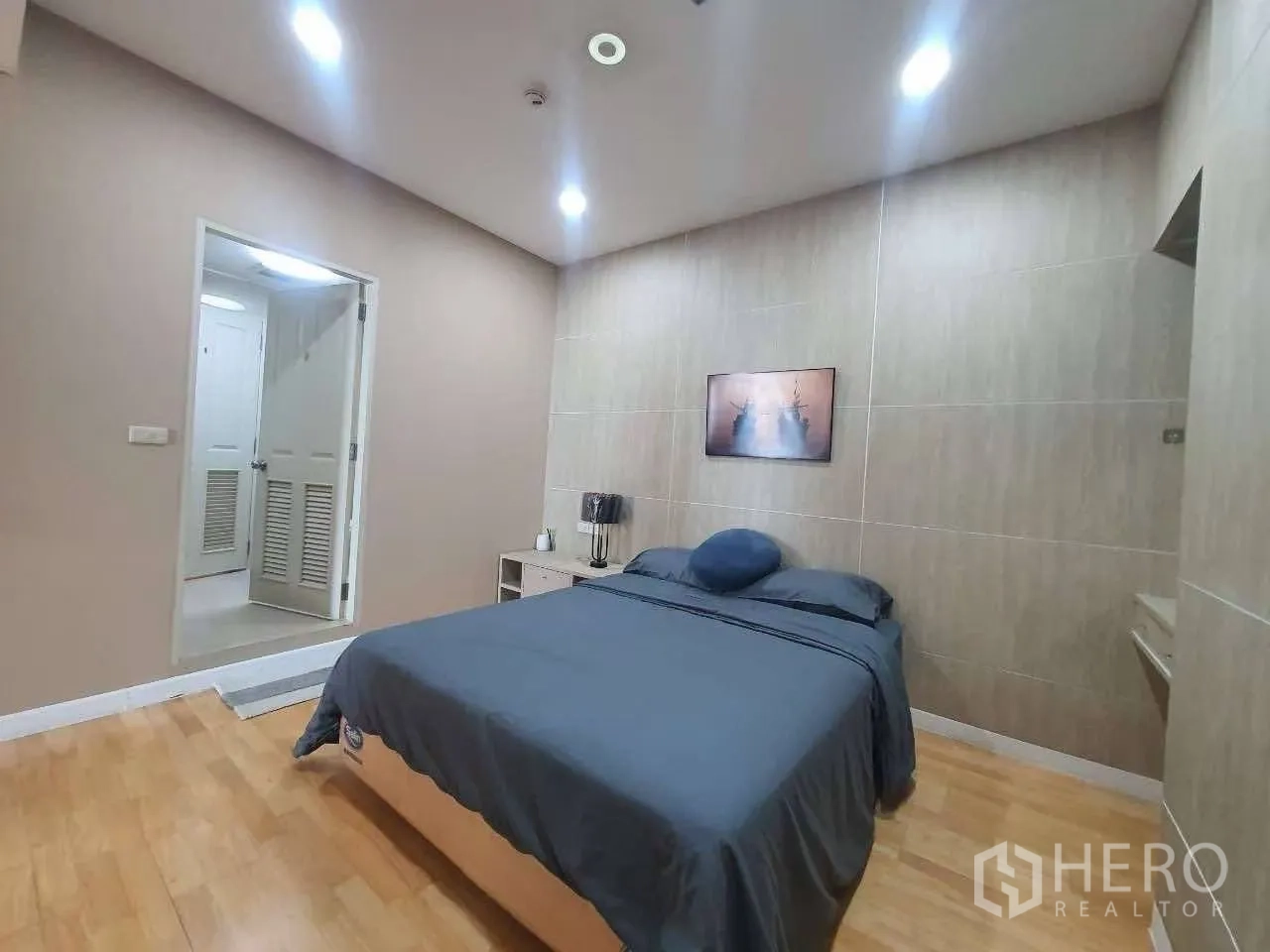 Condominium for rent in Khlong San, Bangkok - Second bedroom with double bed, recessed lighting, wood flooring, and doorway to the bathroom.