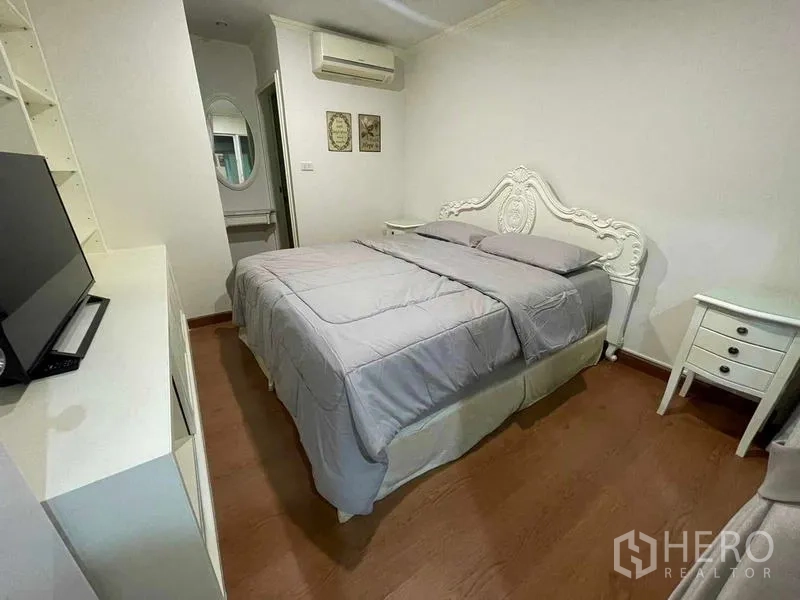 Condominium for rent - Second bedroom with ornate headboard, gray bedding and wall AC.