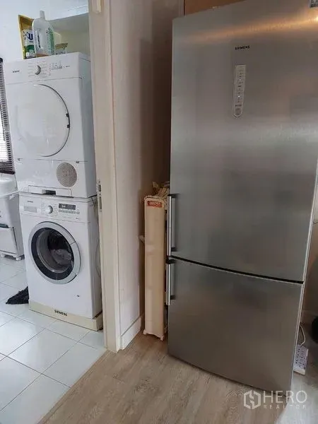 独立式住宅 出售在Khlong Sam Wa, Bangkok - 洗衣区配叠放洗衣机和烘干机，旁边是不锈钢冰箱。