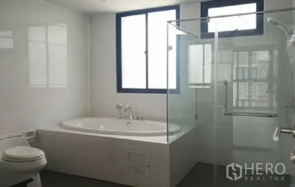 Townhouse for rent in Yan Nawa, Bangkok - Bright bathroom with a corner bathtub, glass-enclosed shower and window for natural light.