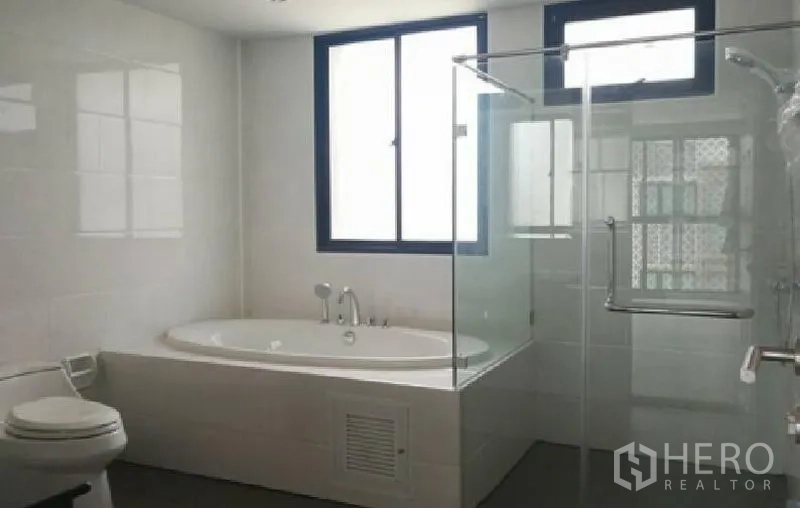Townhouse for rent in Yan Nawa, Bangkok - Bright bathroom with a corner bathtub, glass-enclosed shower and window for natural light.