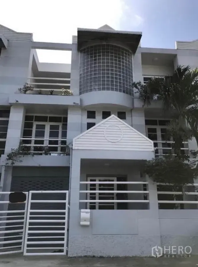 Townhouse for rent in Suan Luang, Bangkok - Modern three-storey townhouse exterior with glass-block bay window, balconies and white railings.