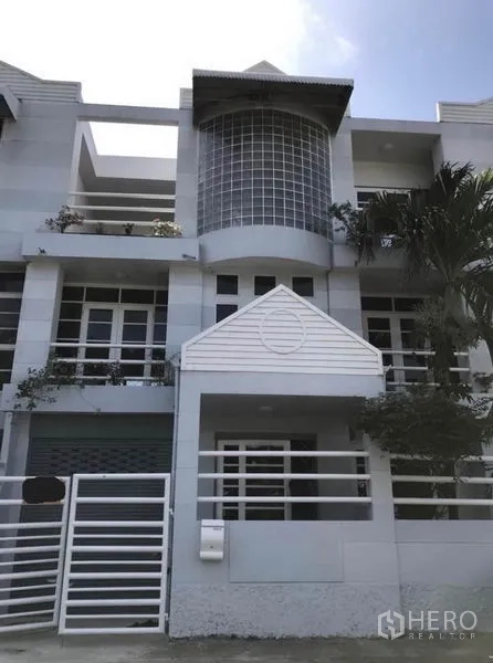 Townhouse for rent in Suan Luang, Bangkok - Modern three-storey townhouse exterior with glass-block bay window, balconies and white railings.