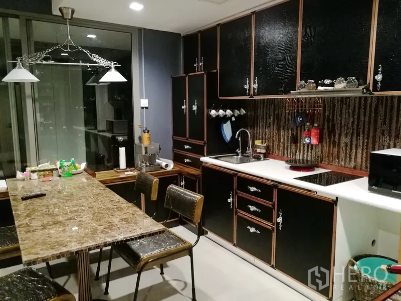 公寓 出租或出售在Bang Kho Laem, Bangkok - 厨房特写，展示橱柜、水槽、电磁炉和石质餐桌。