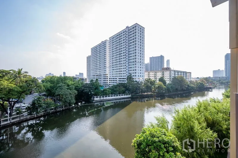 Condominium for rent in Watthana, Bangkok - Canal and city skyline view from the balcony with lush greenery.